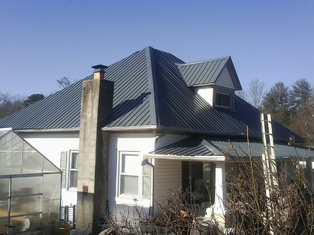 Dark blue standing seam metal roof on a white farmhouse with dormer — Slate & Tile Roof Repair by Roofing Brothers in Montour