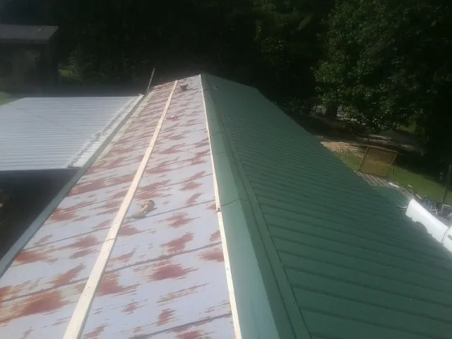 Old rusted panels beside newly installed green metal roofing — Wind Damage Roof Repair by Roofing Brothers in Montour