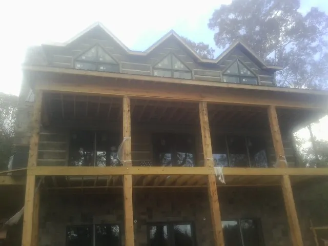 Dormers and porch framing on a large log home under construction — Roof Coating work by our crew in Montour