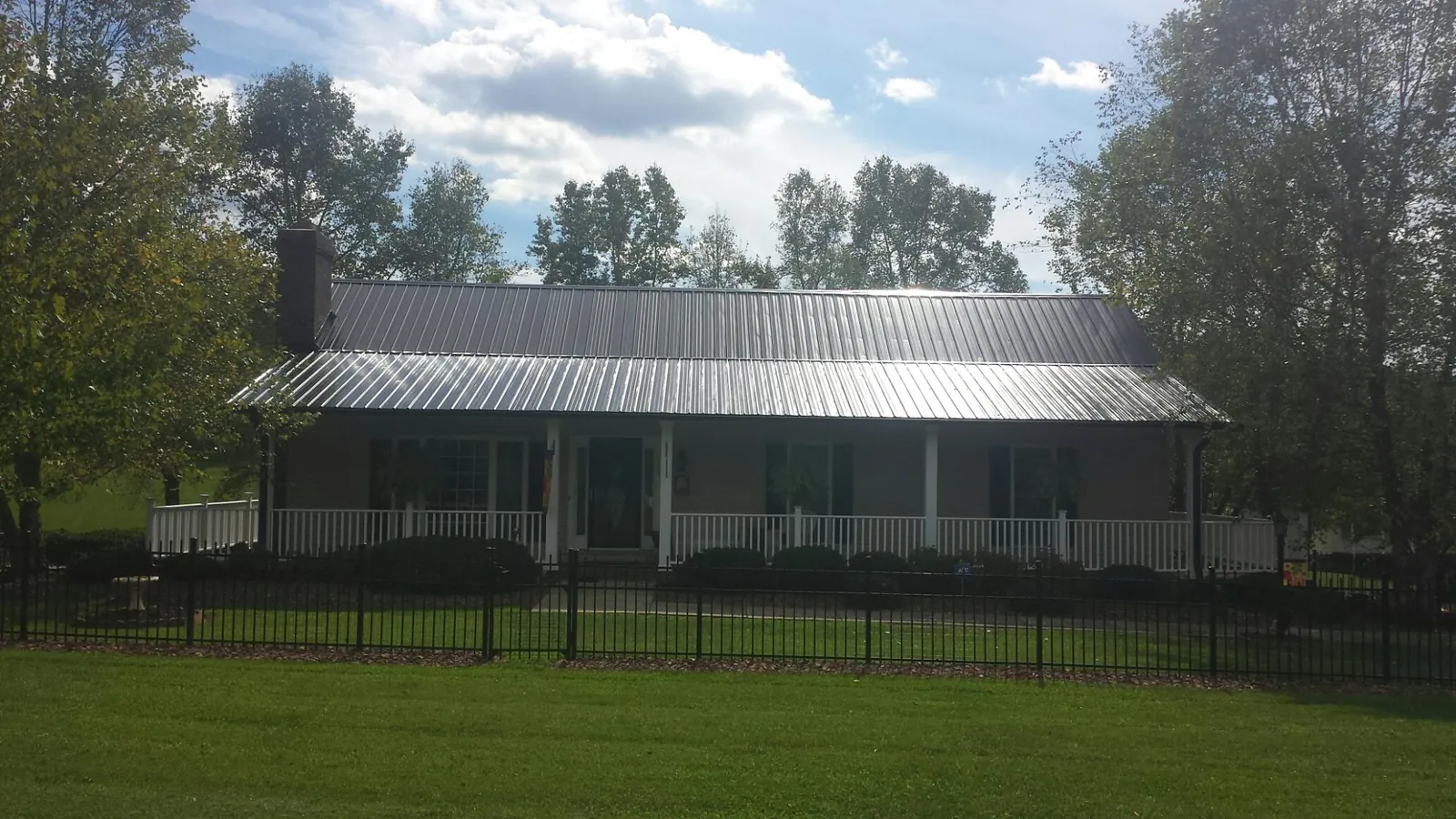Gray metal roof on a brick ranch with a full width front porch — Gutter Guard Installation work by our crew in Montour