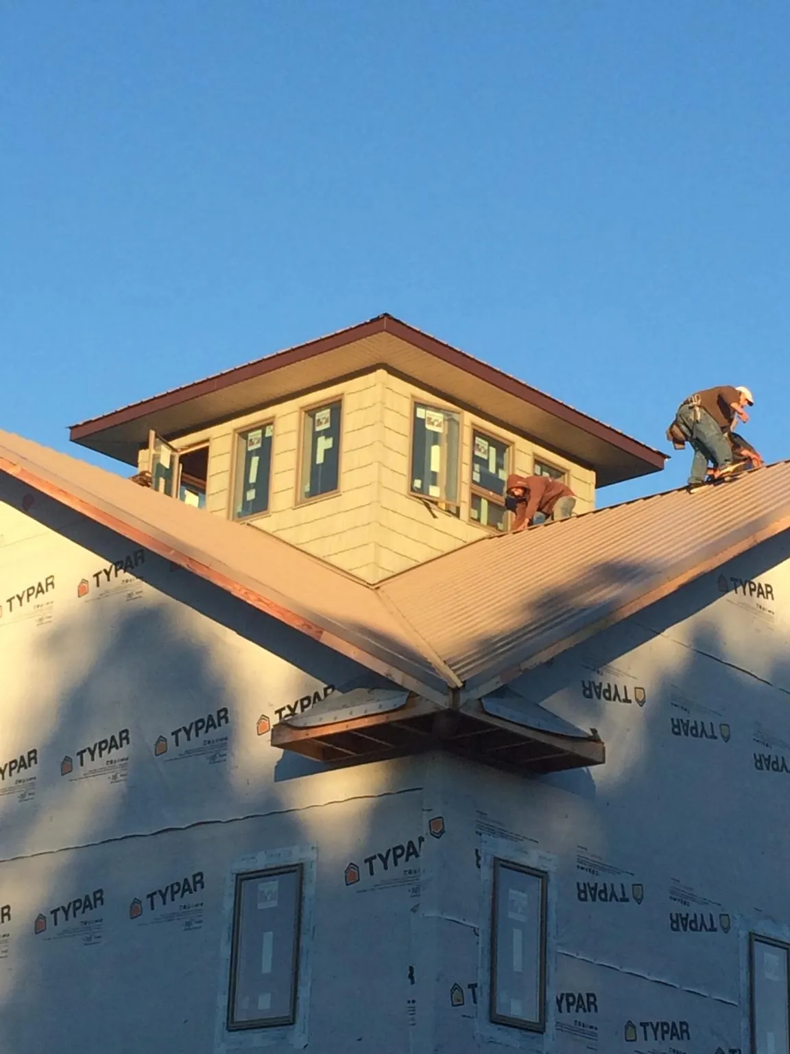 Roofers working around a rooftop cupola on a new metal roof at sunset — Roof Waterproofing in Montour by Roofing Brothers